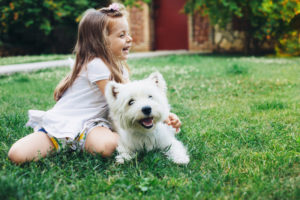 Little girl has fun playing in her backyard with her white dog.