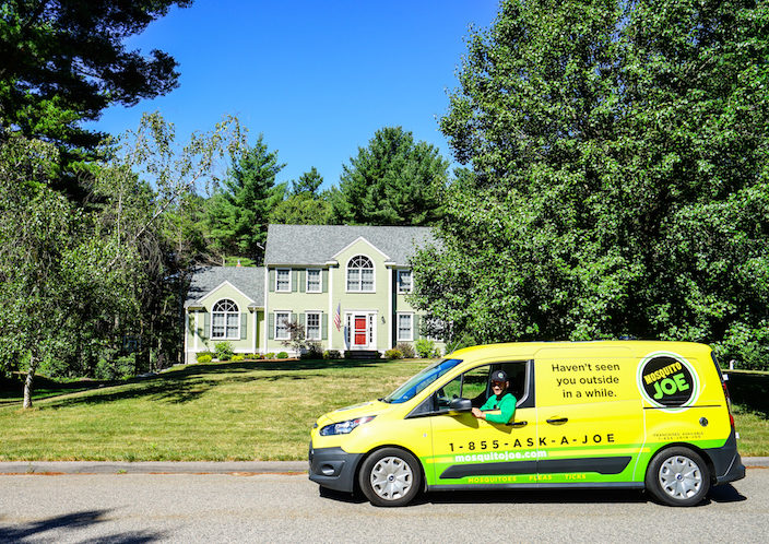 Technician from Mosquito Joe of Gold Coast, CT, in his service van, posing for a picture in front of a house in Connecticut